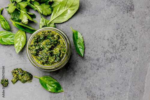 Chimichurri sauce. Argentine green parsley basil sauce chimichurri for barbecue asado in glass jar, gray slate background photo