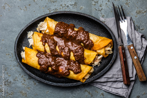 Mexican cuisine. Traditional Mexican chicken enchiladas with spicy chocolate salsa mole poblano. Enchiladas with sauce moole from Puebla, Mexico photo