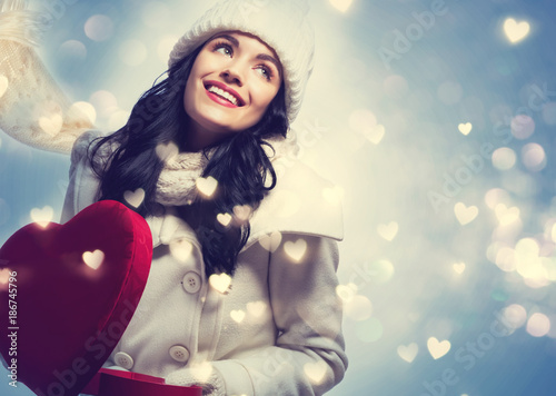 Happy young woman holding a big heart gift box