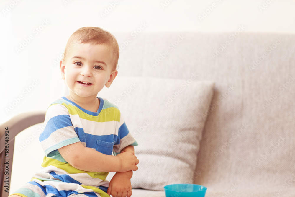 Smiling toddler seating on a grey sofa Smiling toddler seating on a grey sofa