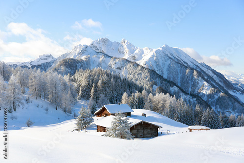 Winter scene. Traditional alpine hut with mountains on background 
