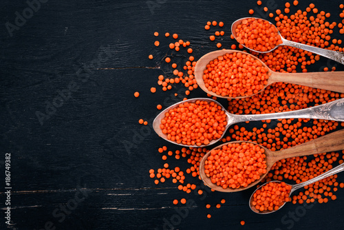 Orange lentils in a spoon. On a wooden background. Top view. Copy space.
