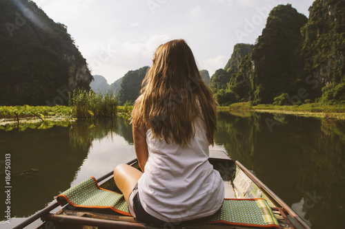 Rear view of woman looking at view while traveling in boat on river photo