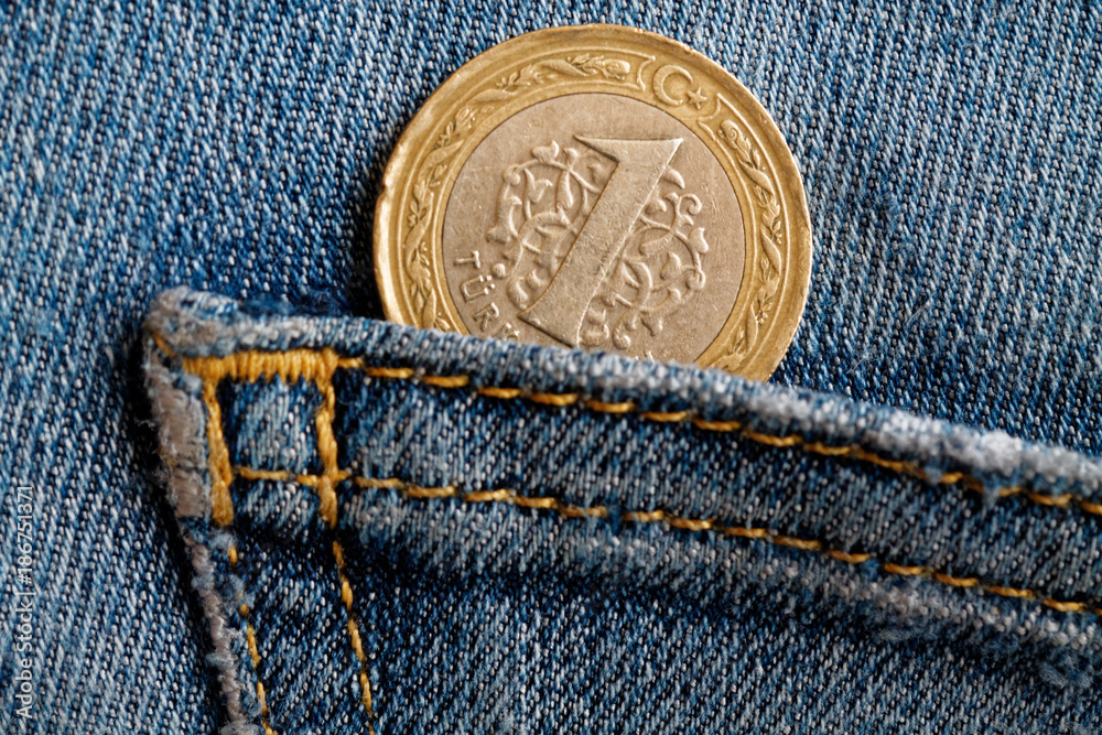 Turkish coin with a denomination of 1 lira in the pocket of blue worn denim jeans Turkish coin with a denomination of 1 lira in the pocket of blue worn denim jeans