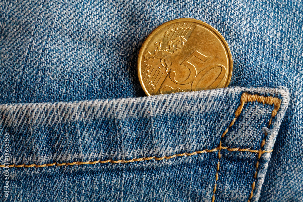Euro coin with a denomination of fifty euro cents in the pocket of old blue worn denim jeans Euro coin with a denomination of fifty euro cents in the pocket of old blue worn denim jeans