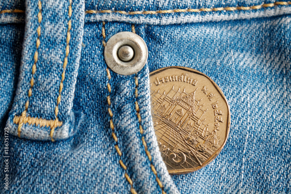 Thai coin with a denomination of five baht in the pocket of worn light blue denim jeans Thai coin with a denomination of five baht in the pocket of worn light blue denim jeans