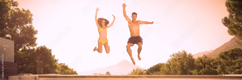 Obraz premium Cheerful couple jumping into swimming pool