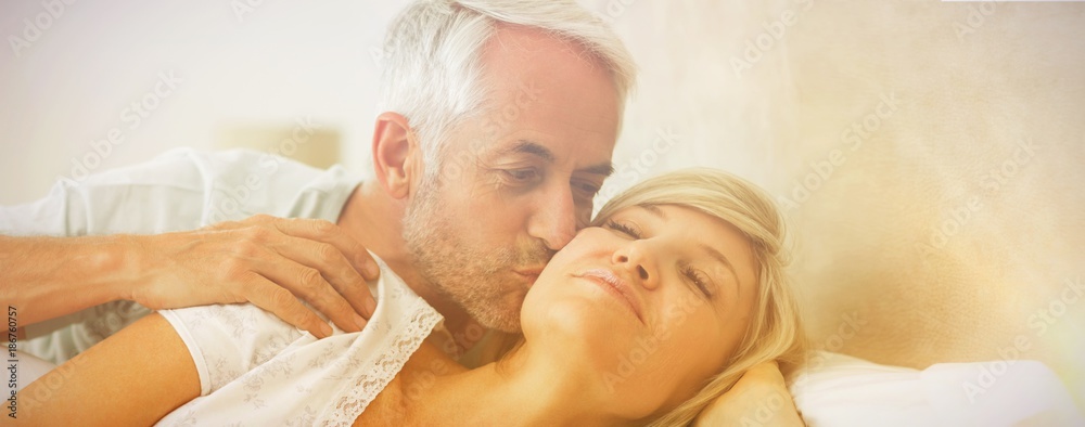 Mature man kissing womans cheek in bed