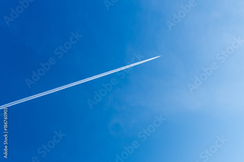 Aeroplane against blue sky and white vapour trail