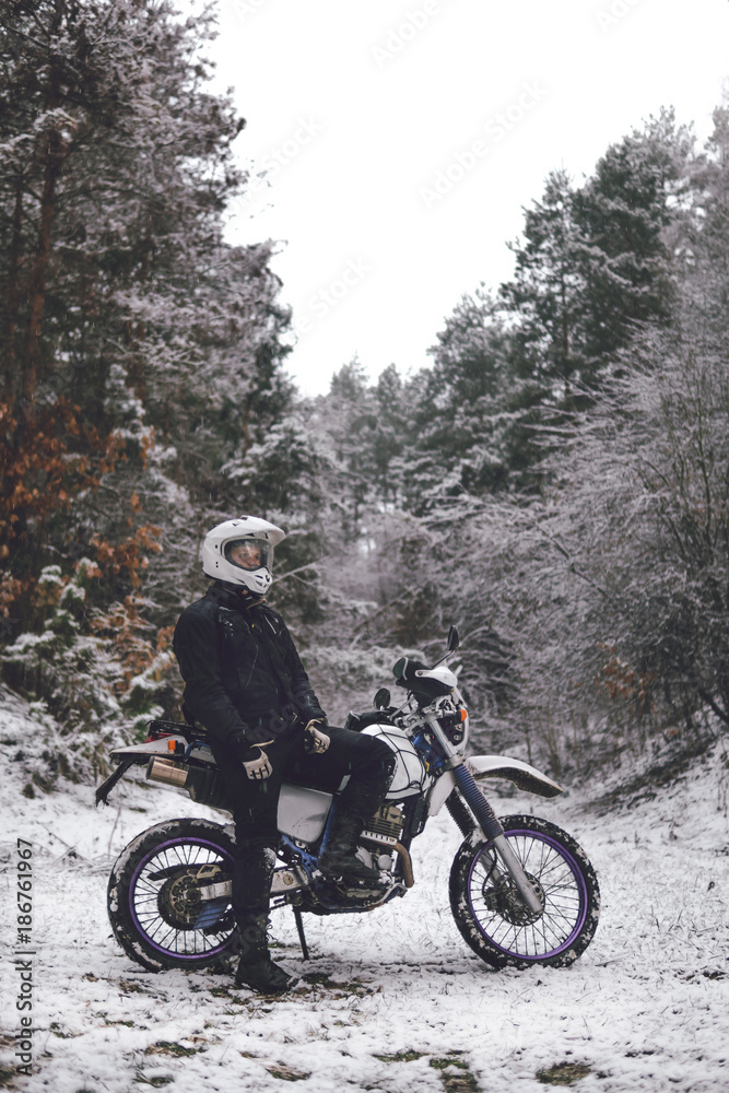 Rider man on a motorcycle Winter motocross. Skid on a snowy forest. the snow from under the wheels of a motorcycle Enduro. off road dual sport travel tour, active life style concept vertical