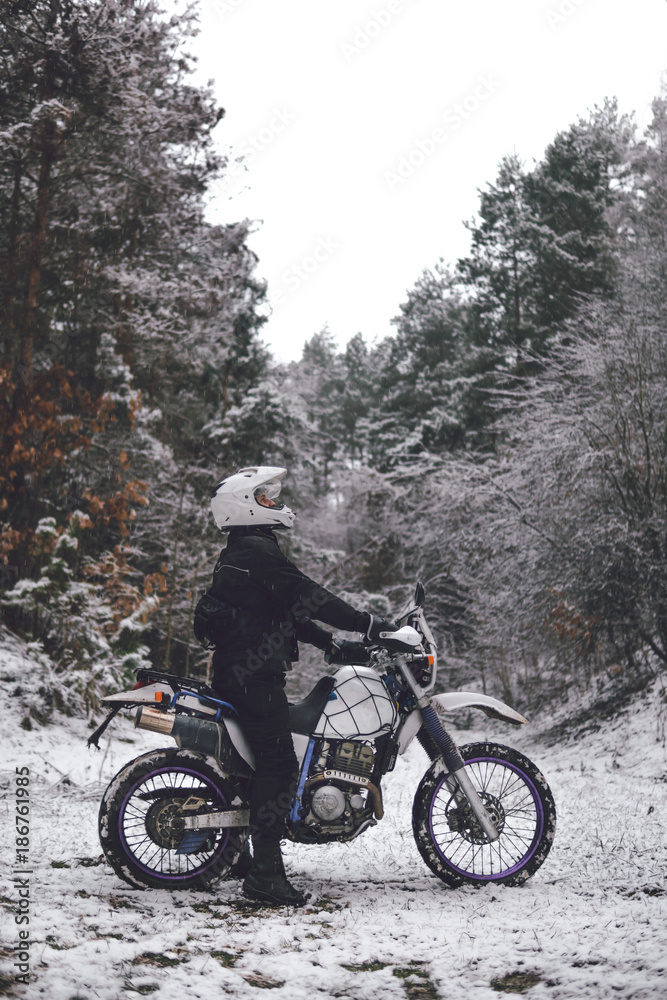 Rider man on a motorcycle Winter motocross. Skid on a snowy forest. the snow from under the wheels of a motorcycle Enduro. off road dual sport travel tour, active life style concept vertical