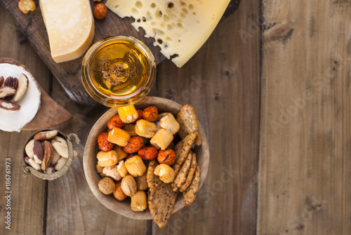 different cheese classic choice, on an old wooden board, nuts, snacks and a glass of beer