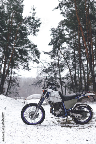 Motorcycle in a winter forest snow on the background of snowy trees. Winter extreme fun. Motorcycling in the winter. extreme fun in winter on a motorbike, enduro off road dual sport travel