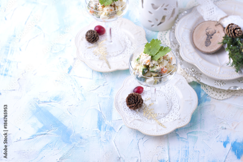 traditional New Year's Russian salad of vegetables and meat, with mayonnaise. Served in a glass and decorated with parsley, on a white table