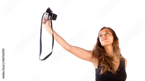 Pretty happy girl taking a selfie with a vintage camera; isolated on white, customizable background with copy space