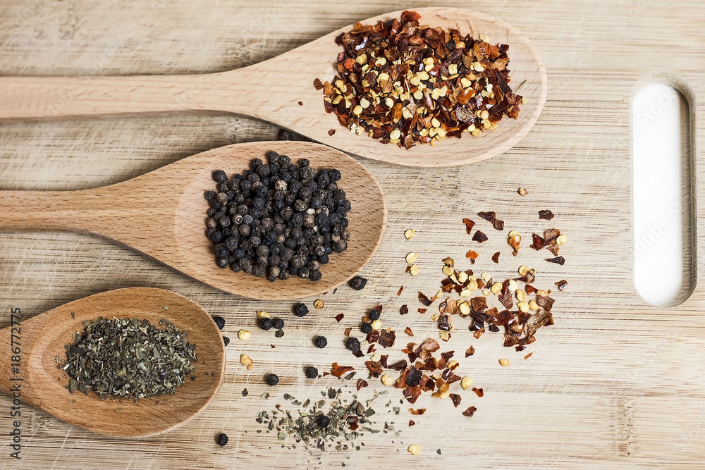 Mixed herbs in wooden spoons. Chilli flakes, grainy pepper and dried basil. Mixed herbs in wooden spoons. Chilli flakes, grainy pepper and dried basil.