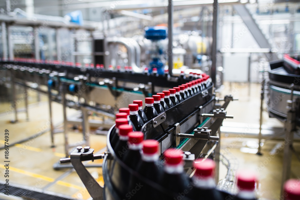 Bottling factory - Black juice bottling line for processing and bottling juice into bottles. Selective focus. 
