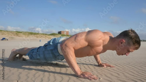 Young Body builder doing pull ups in summer day outdoor