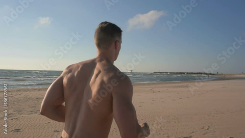 Young handsome sportive man jogging at the beach