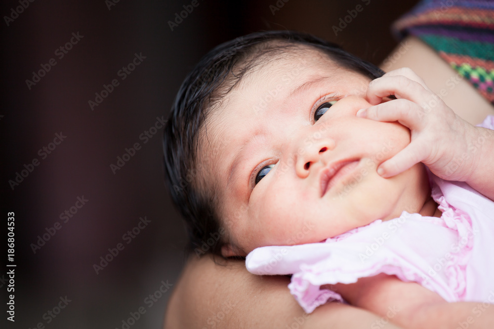 Cute asian newborn baby girl resting on mother's arm. Mom cuddling baby with tenderness. Cute asian newborn baby girl resting on mother's arm. Mom cuddling baby with tenderness.