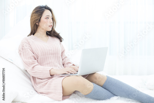 Attractive female using laptop at bedroom. People lifestyle concept.