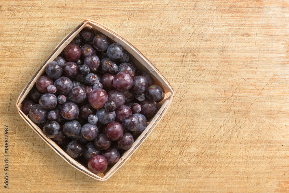 Pint container of concord grapes on a wood counter with copy space Pint container of concord grapes on a wood counter with copy space