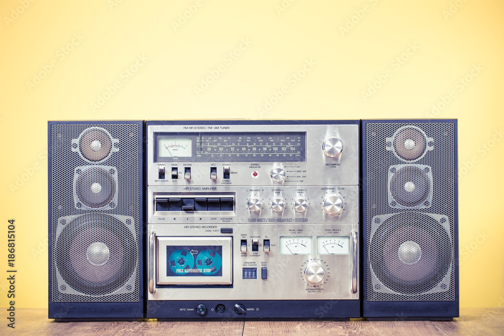 Retro outdated stereo boombox radio cassette recorder circa 1980s front yellow background. Vintage old style filtered photo