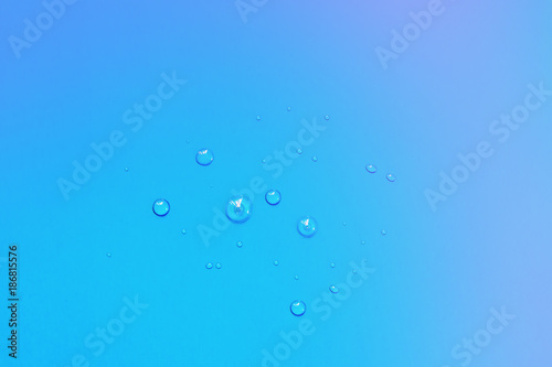 Small drops of water close-up in a bright blue cardboard surface, abstract background