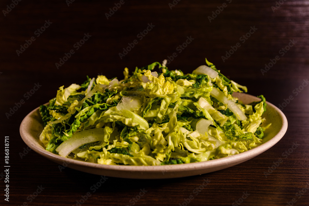 Salad with the savoy cabbage in the dish on dark wooden table Salad with the savoy cabbage in the dish on dark wooden table