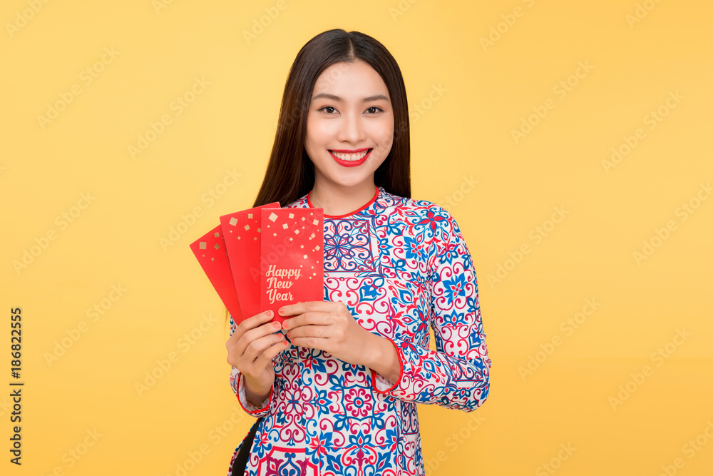 Pretty smiling Vietnamese woman with red envelopes isolated over yellow background Pretty smiling Vietnamese woman with red envelopes isolated over yellow background