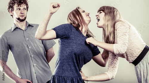 Foto Aggressive mad women fighting over man.