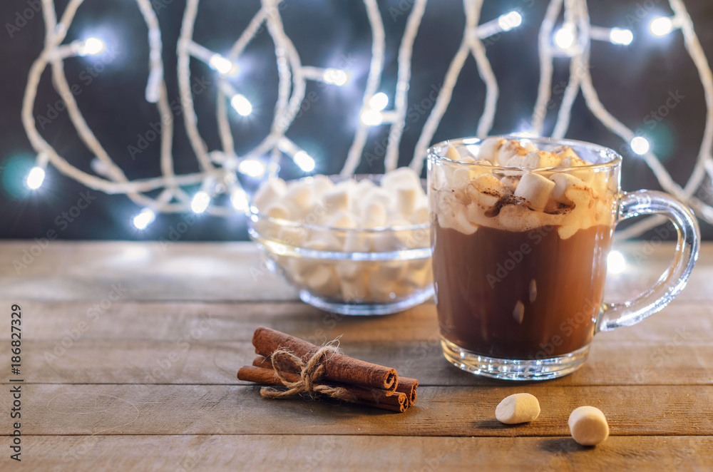 Hot chocolate, cinnamon sticks and marshmallow on the background of burning garlands, Christmas decorations, close up Hot chocolate, cinnamon sticks and marshmallow on the background of burning garlands, Christmas decorations, close up