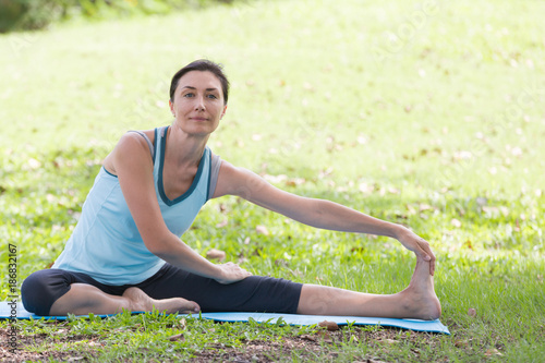 Holiday young woman doing yoga pose meditation in the public park Sport Healthy concept.