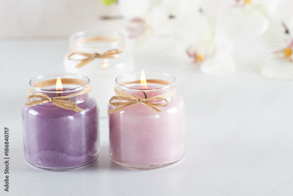 Burning purple, pink and white candles on white table Burning purple, pink and white candles on white table