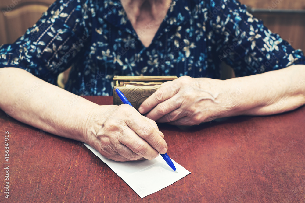 An elderly woman with a purse in her hand writes on blank paper