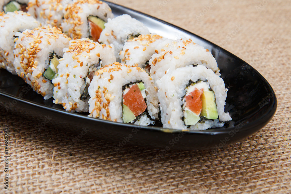 Uramaki sushi rolls with avocado and red fish on ceramic plate Uramaki sushi rolls with avocado and red fish on ceramic plate