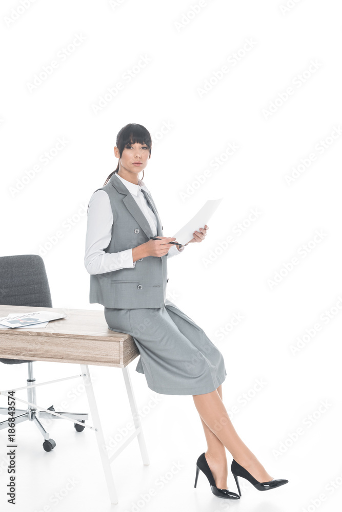 businesswoman leaning on table and holding documents isolated on white