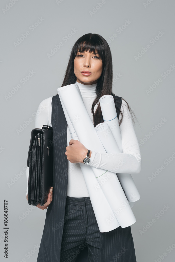 businesswoman standing with briefcase and blueprints isolated on gray businesswoman standing with briefcase and blueprints isolated on gray