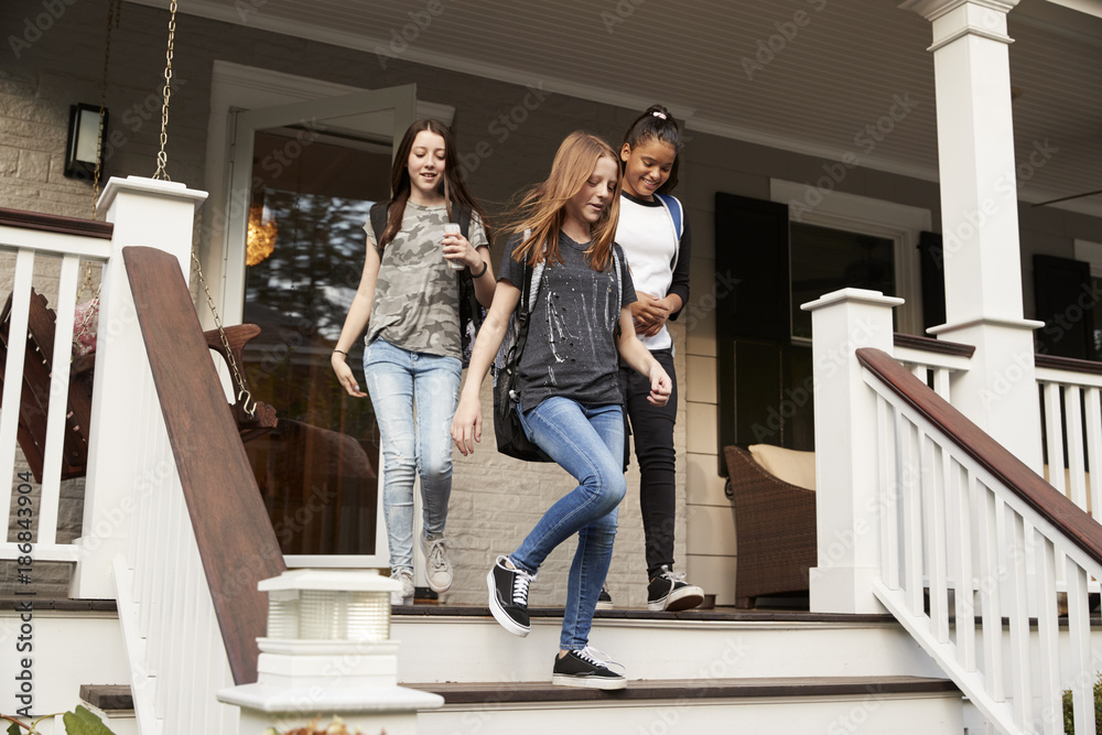 Three teen girls leaving house with school bags