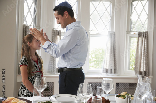 Photography Jewish father blesses daughter by table set for Shabbat meal