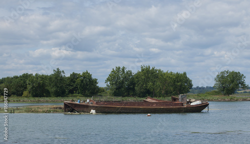 photo of an old rusting boat tied-up with trees in the background 