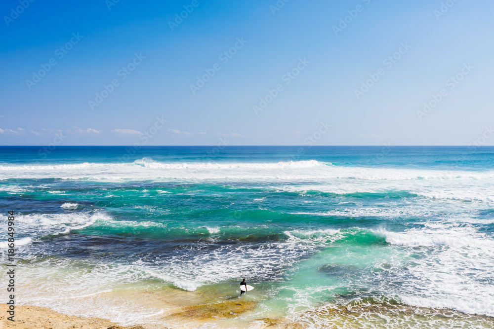 A single surfer stands at the short at the famous Margaret River beach, in the South West of Western Australia, Australia. A single surfer stands at the short at the famous Margaret River beach, in the South West of Western Australia, Australia.