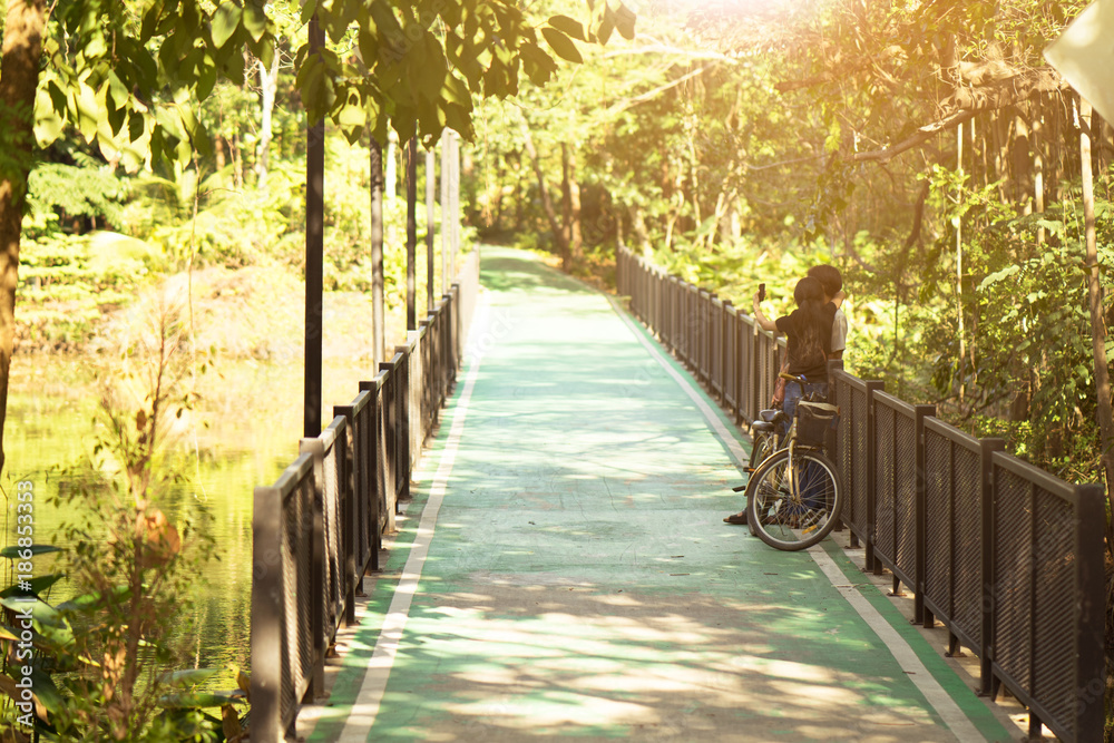 Couples are couple photos in biking path at the public park with sunset. Concept love in valentines ‘day.