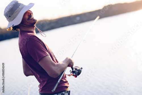Men fishing in sunset and relaxing while enjoying hobby © NDABCREATIVITY