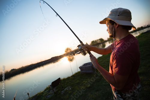 Young man fishing at pond and enjoying hobby