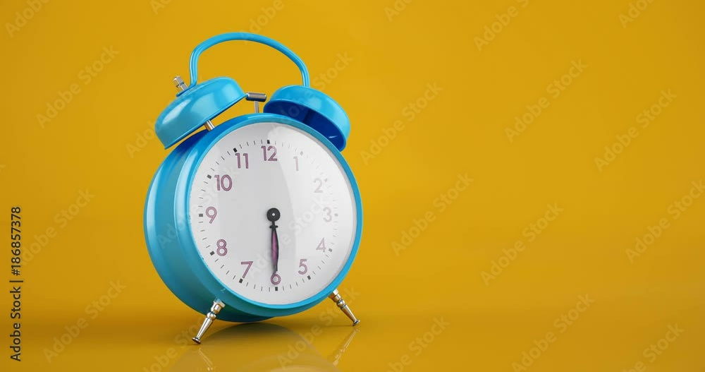 Blue vintage alarm clock time lapse copy space warm yellow background