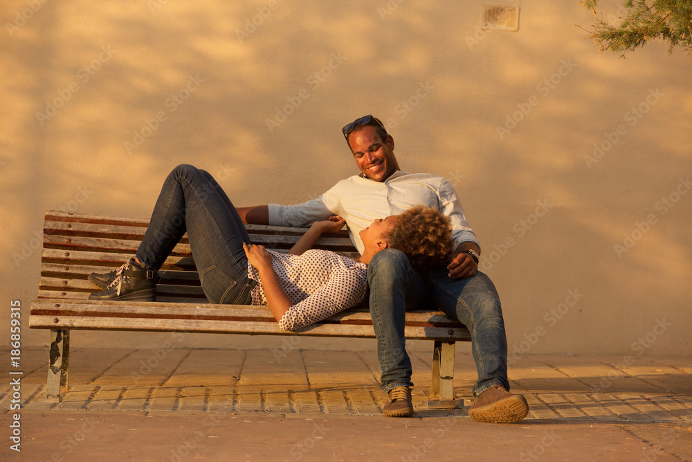 Obraz premium happy couple sitting on park bench outside