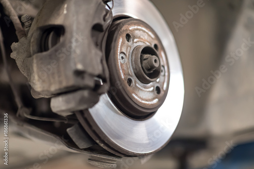 change the old drive to the Brand new brake disc on car in a garage. Auto mechanic repairing .