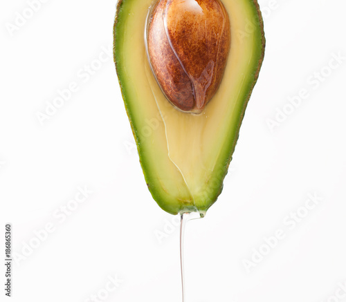 Dripping oil on a cut avocado on a white background
