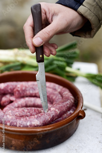 piercing a raw pork meat sausage before to cook it